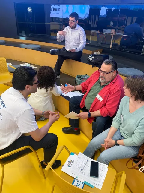 Un grupo de asistentes conversa en las gradas amarillas del HUB Por Talento Digital durante una dinámica