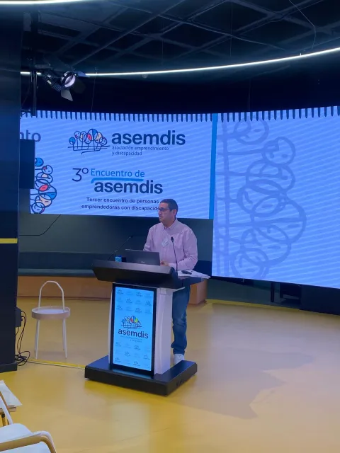 Un ponente interviene desde el atril de ASEMDIS ante la pantalla del 3.º Encuentro
