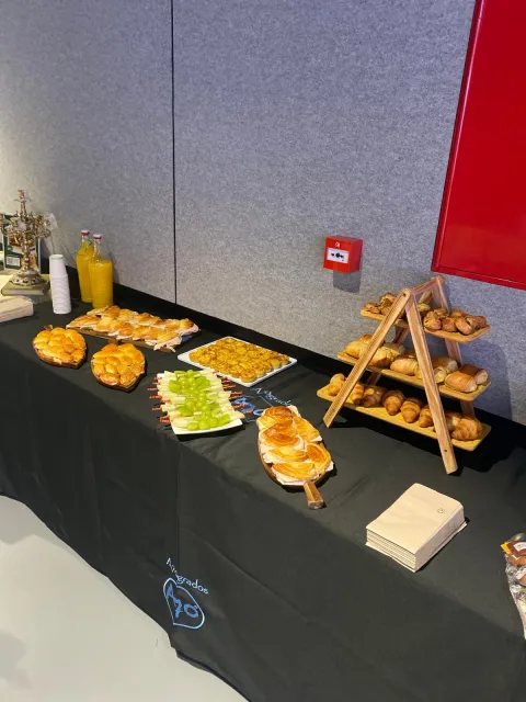 Mesa del café con bollería, fruta y zumos para las personas asistentes