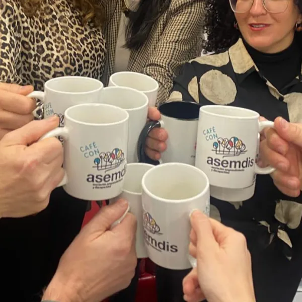 Varias manos brindan con tazas de «Café con asemdis»
